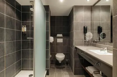 a bathroom with a toilet and a sink and a shower at NYX Hotel Amsterdam Rembrandt Square in Amsterdam