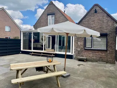 a picnic table with an umbrella in front of a house at welkom bij 5 in Den Ilp
