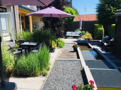 a patio with an umbrella and a pond at Holiday in Spakenburg Groof in Spakenburg