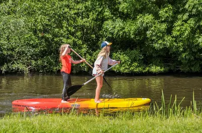 two girls on a paddle board in the water at Camping De Boerinn in Kamerik