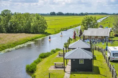 a river with a house and a boat in it at Camping De Boerinn in Kamerik
