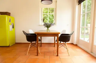 a dining room table with black chairs and a yellow refrigerator at Het Eerste Huisje vacation home in Noordwijk aan Zee