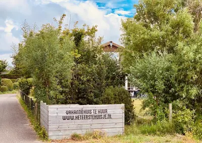 a sign in front of a house on a road at Het Eerste Huisje vacation home in Noordwijk aan Zee