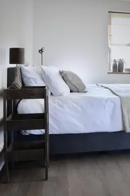 a bedroom with a bed with white sheets and a chair at Bedje in de polder in Montfoort