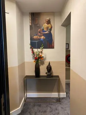 a table in a hallway with a painting on the wall at NL Hotel District Leidseplein in Amsterdam