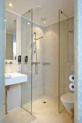 a bathroom with a glass shower with a sink and a toilet at NL Hotel District Leidseplein in Amsterdam