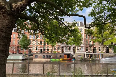 a house boat on a river in front of a building at NL Hotel District Leidseplein in Amsterdam