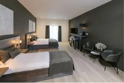 a hotel room with two beds and a desk at Hotel De Rustende Jager in Nieuw-Vennep