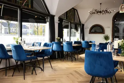 a restaurant with blue chairs and tables and windows at Hotel De Rustende Jager in Nieuw-Vennep