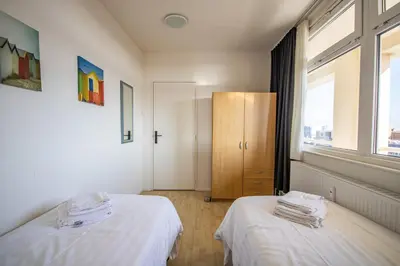 a room with two beds and a cabinet with windows at The Lookout in Egmond aan Zee