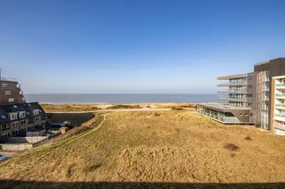 a grassy hill with buildings and the ocean in the background at The Lookout in Egmond aan Zee