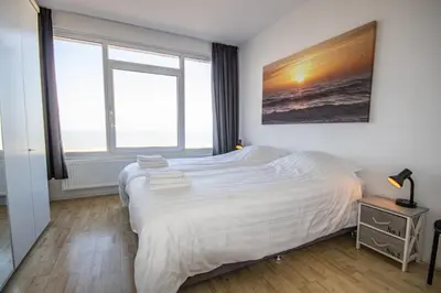 a bedroom with a bed and a large window at The Lookout in Egmond aan Zee