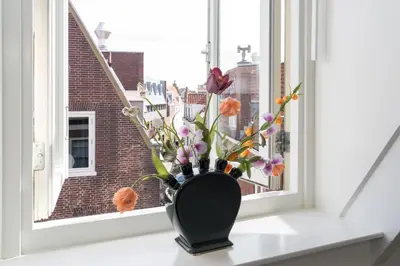 a black vase with flowers sitting on a window sill at Six Boutique Hotel in Haarlem