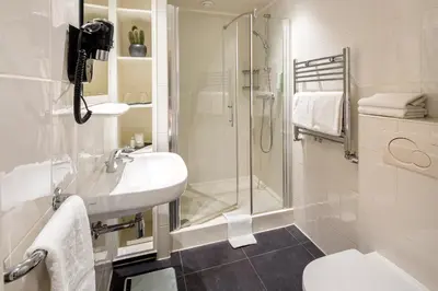 a white bathroom with a shower and a sink at Hotel Sint Nicolaas in Amsterdam