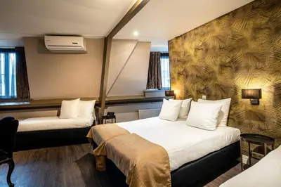 a hotel room with two beds and a desk at Hotel Sint Nicolaas in Amsterdam