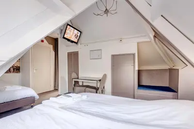 a bedroom with a bed and a desk with a tv at Hotel Stad en Land in Alkmaar