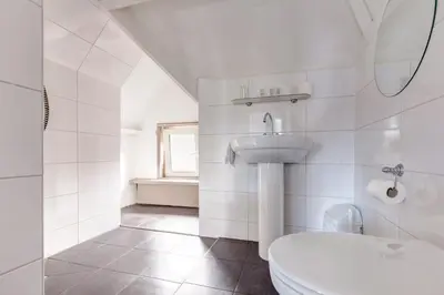 a white bathroom with a toilet and a sink at Hotel Stad en Land in Alkmaar