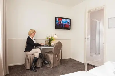 a woman sitting at a table with a laptop at Hotel Stad en Land in Alkmaar
