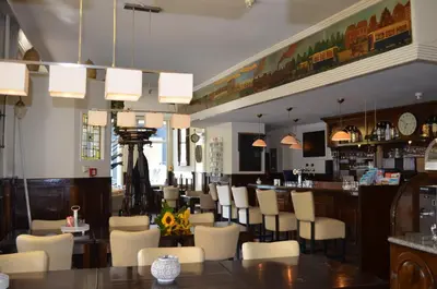a restaurant with a bar with white chairs at Hotel Stad en Land in Alkmaar