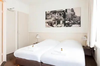 two white beds in a room with a picture on the wall at Hotel Stad en Land in Alkmaar