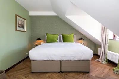 a bedroom with a large bed with green walls at Boetiekhotel De Kastanjehof in Lage-Vuursche