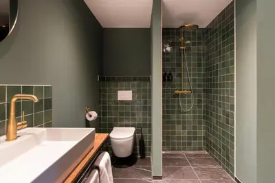 a bathroom with a sink and a toilet and green tiles at Boetiekhotel De Kastanjehof in Lage-Vuursche