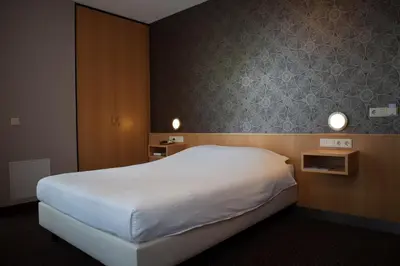 a bedroom with a large white bed and two lights at Hotel Aalsmeer in Aalsmeer