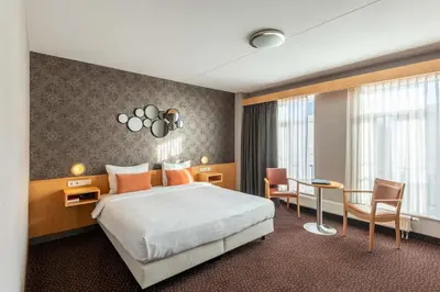 a hotel room with a bed and a table and chairs at Hotel Aalsmeer in Aalsmeer
