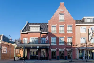 a large red brick building with a balcony at Hotel Aalsmeer in Aalsmeer