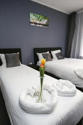 a room with two beds with a vase with a flower in it at Hotel Flipper Amsterdam in Amsterdam