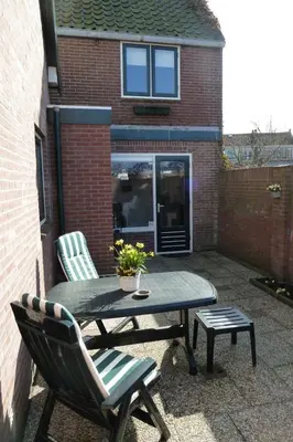 a patio with a table and a chair and a table and a bench at De Vrije Vogel in Egmond aan Zee