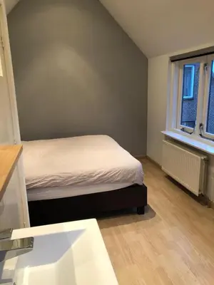 a small bedroom with a bed and a window at De Vrije Vogel in Egmond aan Zee