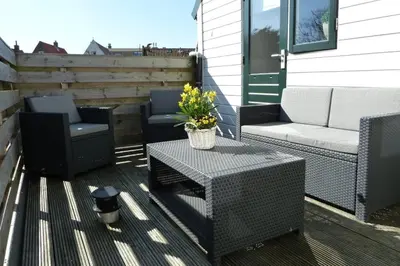 a patio with two chairs and a table with flowers at De Vrije Vogel in Egmond aan Zee