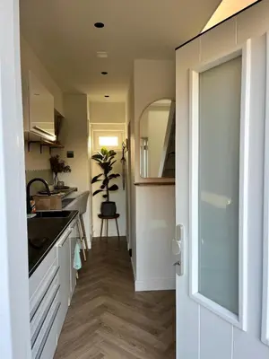 a kitchen with white cabinets and a sink and a mirror at Tiny House in center Aalsmeer I Close to Schiphol & Amsterdam in Aalsmeer
