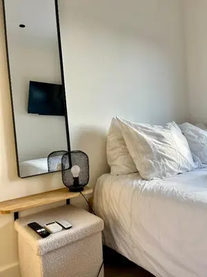 a bedroom with a bed with a mirror and a stool at Tiny House in center Aalsmeer I Close to Schiphol & Amsterdam in Aalsmeer