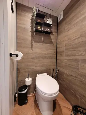 a bathroom with a white toilet and a wooden wall at B&B 't Maartensdijkse Bos in Maartensdijk