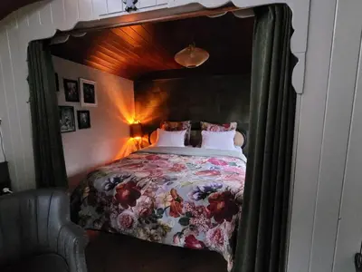 a bedroom with a canopy bed with a floral bedspread at B&B 't Maartensdijkse Bos in Maartensdijk