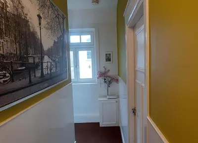 a hallway with a painting on the wall and a window at Bickersbed in Amsterdam