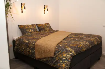a bed with a comforter and pillows in a room at Het Groeneveld in Oudkarspel