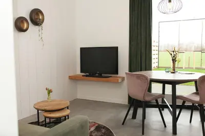 a living room with a table and a tv at Het Groeneveld in Oudkarspel