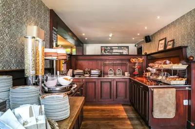 a kitchen with wooden cabinets and plates on a counter at Hotel Victoria in Bergen aan Zee
