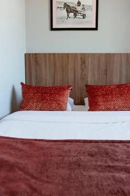 a bedroom with a bed with red pillows at Hotel Victoria in Bergen aan Zee