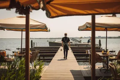 a man walking down a dock next to the water at De Durgerdam, Amsterdam in Amsterdam