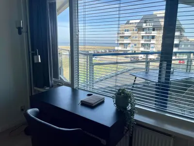a table with a book in front of a window at Sterflat 67 in Egmond aan Zee