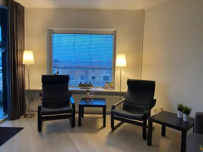 a living room with two chairs and a table and a window at Sterflat 67 in Egmond aan Zee