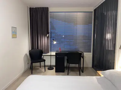 a bedroom with a desk and two chairs in front of a window at Sterflat 67 in Egmond aan Zee