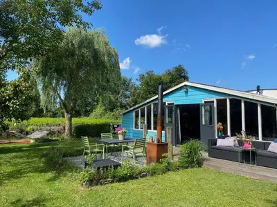 a blue house with a table and chairs in the yard at Beautiful house on an island near Amsterdam in Oude Meer