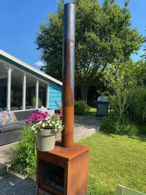a wood stove with a pot of flowers in a yard at Beautiful house on an island near Amsterdam in Oude Meer