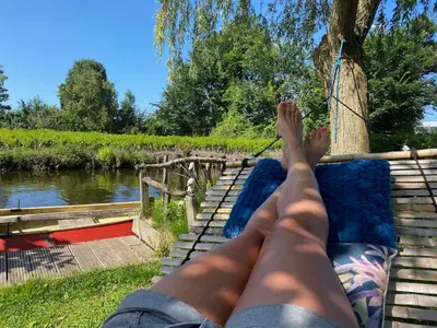a person laying on a bench next to a river at Beautiful house on an island near Amsterdam in Oude Meer