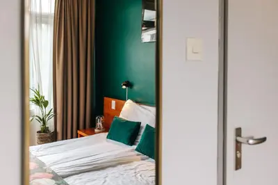 a bedroom with a bed with a green wall at Hotel Keur in Zandvoort